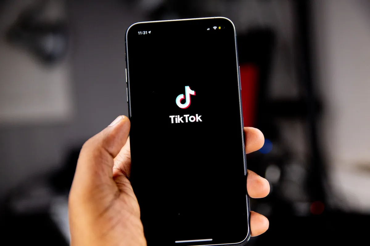 Mano sosteniendo un celular con el logo de TikTok en la pantalla